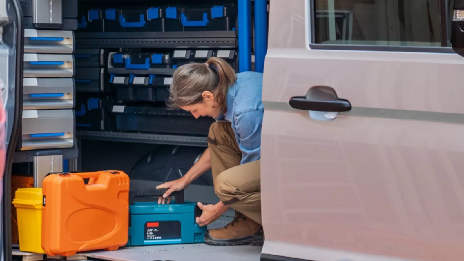 Handwerkerin belädt den Laderaum eines VW Crafter Kastenwagen