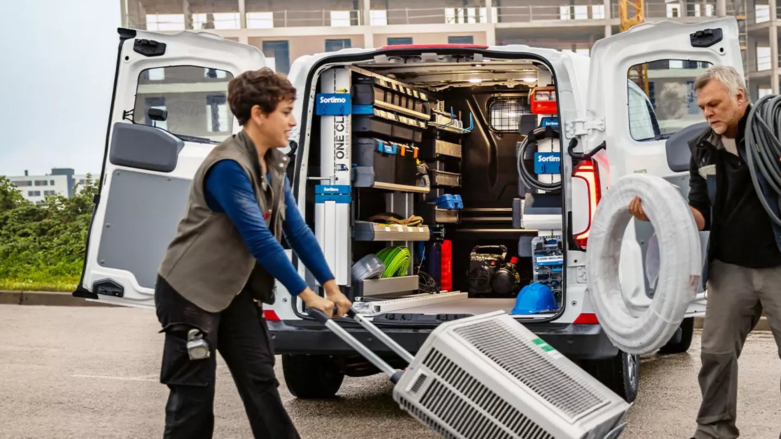 Handwerker entladen einen VW Transporter Kastenwagen mit Regaleinbau