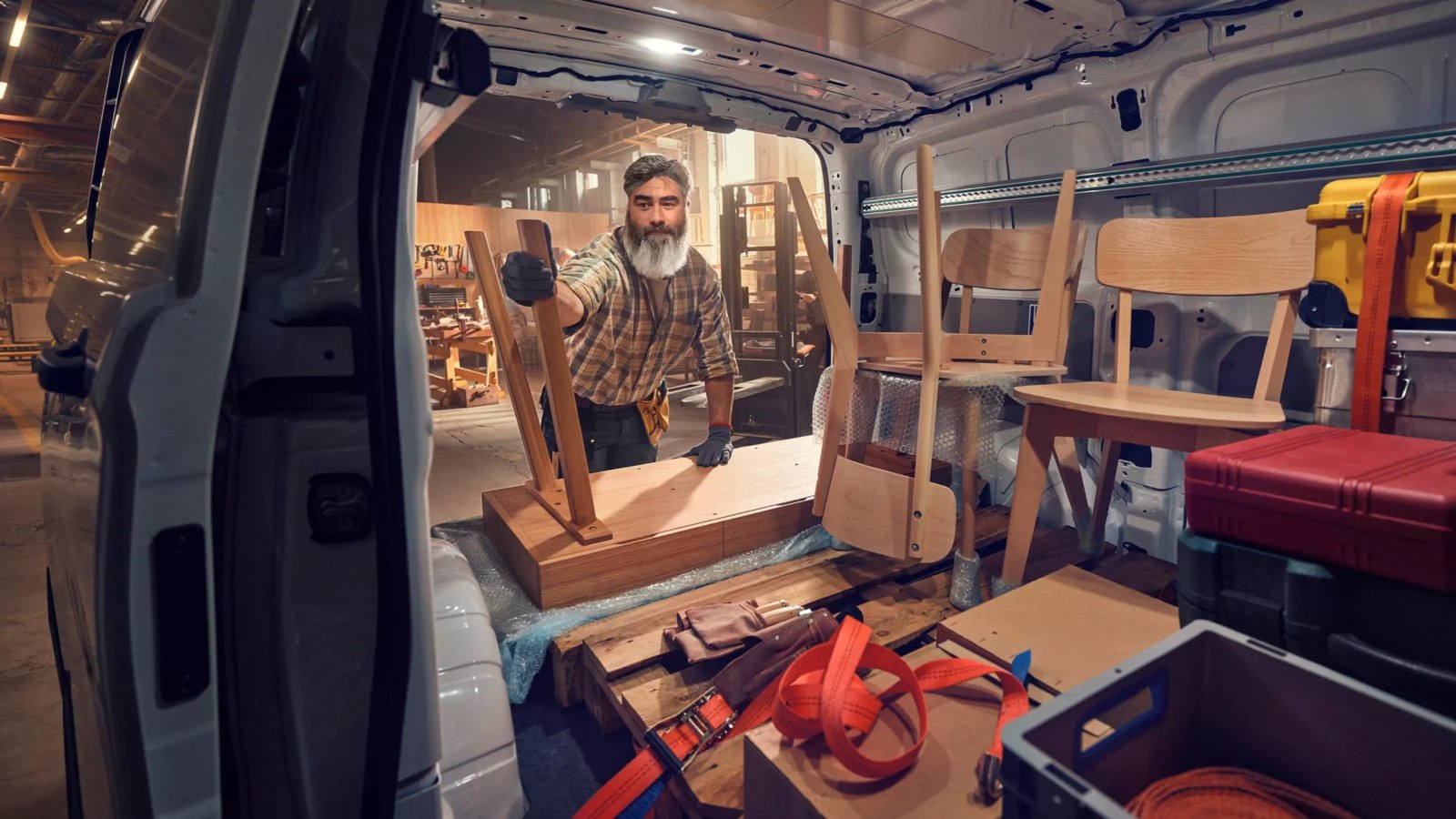 Ein Tischler verstaut Möbel im Laderaum eines VW Transporter
